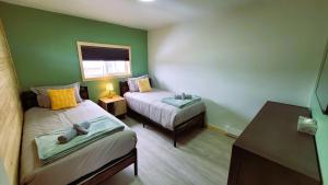 Habitación pequeña con 2 camas y mesa. en Caribou Cottage, en Churchill