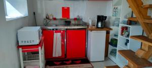 een kleine keuken met rode kasten en een wastafel bij Maison La Thébaïde in Castéra-Lectourois
