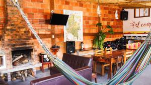 a hammock in a restaurant with a table and a fireplace at Hostal El Caminante in El Cocuy