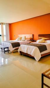 Duas camas num quarto com uma parede laranja em Hotel Wellness - Belleza y Serenidad em Boca del Río