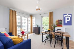 - un salon avec un canapé bleu et une table dans l'établissement SuperApart Okrzei 12, à Varsovie