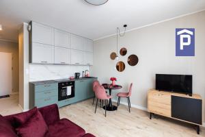 uma cozinha e sala de estar com um sofá e uma mesa em SuperApart Omulewska em Varsóvia
