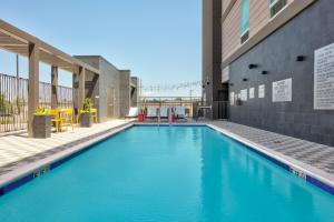 亨茨維爾的住宿－Home2 Suites By Hilton Huntsville, Tx，一座大型蓝色游泳池,位于大楼旁边