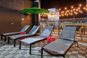 a row of chairs with an umbrella on a patio at Home2 Suites By Hilton Huntsville, Tx in Huntsville