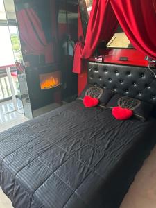 ein Schlafzimmer mit einem schwarzen Bett mit roten Kissen und einem Kamin in der Unterkunft Rez de jardin OU ascenseur 4 ieme PISCINE -WIFI-Village naturiste holidaysochic in Cap d'Agde