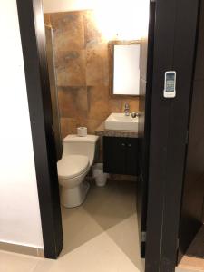 ein Badezimmer mit einem WC, einem Waschbecken und einem Spiegel in der Unterkunft KIWi MONTAÑITA in Montañita