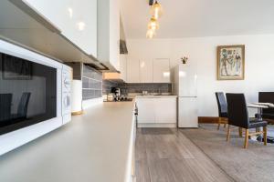 Modern 2 bedroom apartment in Mitcham, London في ميتشام: مطبخ وغرفة معيشة مع تلفزيون بشاشة مسطحة