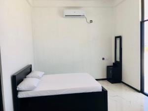 Dormitorio blanco con cama con sábanas y almohadas blancas en SHAKIN SHASHA BEACH HOUSE, en Jaffna