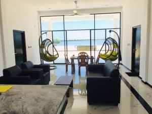 d'un salon avec des chaises, une table et une grande fenêtre. dans l'établissement SHAKIN SHASHA BEACH HOUSE, à Jaffna