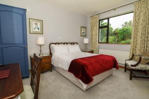 a bedroom with a bed with a red blanket and a window at An Dooneen, The Hurley Farm B&B in Ballydavid