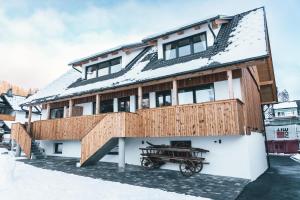 une maison avec une terrasse dans la neige dans l'établissement Podlipnik Apartments, à Rateče