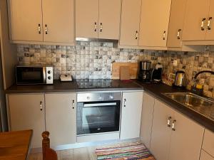 cocina con armarios blancos, fregadero y microondas en Filia's House (The House of Friendship), en Areopoli