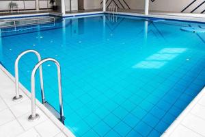 a large swimming pool with blue water at Amelanderkaap 31 met zwembad in Hollum