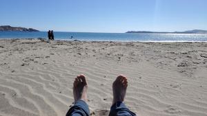 a person laying on a beach with their feet in the sand at Twin Brothers Pichidangui 1 in Pichidangui
