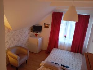 1 dormitorio con 1 cama, 1 silla y TV en Pokoje gościnne u Aleksandry, en Hel
