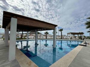a large swimming pool with a pavilion and palm trees at Departamento con alberca en Cerritos! in Mazatlán