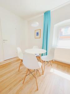 une salle à manger blanche avec des chaises blanches et une table dans l'établissement StayHere Central City Studio 13 - contactless Self-Check-IN, à Graz