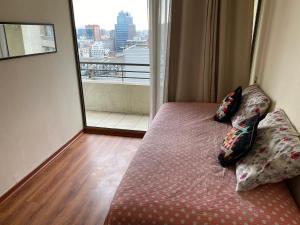 ein Schlafzimmer mit einem Bett mit Kissen und einem Fenster in der Unterkunft Departamento Santiago Centro - Metro Santa Lucia in Santiago + 4 Fotos