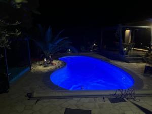 una gran piscina azul por la noche en Partie de villa moderne avec piscine En option jaccuzi dans espace détente indépendant, en Villeneuve