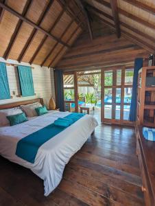 Cama grande en habitación con suelo y ventanas de madera en Indigo Bungalows, en Gili Trawangan