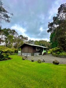 a small house in a yard with rocks in the grass at Volcano Hideaway Cabin as seen on HGTV in Volcano