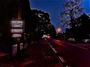 un cartello stradale sul lato di una strada di notte di High Trees Guest House Gatwick a Hookwood