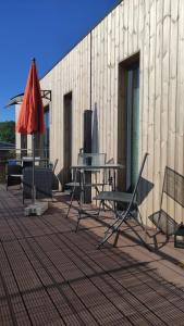 une terrasse avec une table, des chaises et un parasol dans l'établissement Little Tiny Village Haus 2, à Fußach