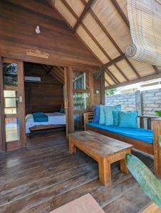 a porch with a bed and a wooden table at Indigo Bungalows in Gili Trawangan +49 photos