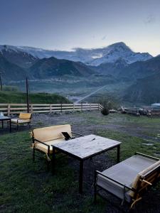 een tafel en stoelen op een veld met bergen bij Kuro Kazbegi • ყურო ყაზბეგი in Kazbegi
