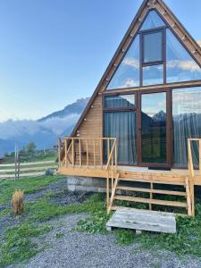 een hut met een groot raam en een terras bij Kuro Kazbegi • ყურო ყაზბეგი in Kazbegi