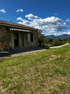 uma casa de pedra com um relvado verde em frente em Le Gast, Vaumeilh em Sisteron