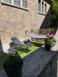 a hammock and a chair in a yard with flowers at Appartement Dio in Dinant
