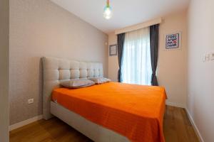 a bedroom with a large bed with an orange blanket at Geppetto Apartment in Podgorica
