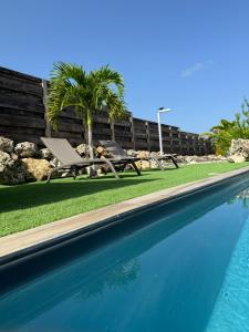 a swimming pool with a picnic table and palm trees at Nakolodge - 2 chambres -piscine et jardin privatifs in Sainte-Anne