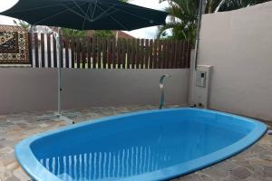 a blue tub sitting in a yard with an umbrella at Casa com piscina e ar condicionado condicionado in Matinhos