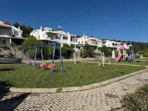 einen Park mit einem Spielplatz mit Rutschen und Schaukeln in der Unterkunft Karaburun'da Yeni Tripleks BegonVİL-LA in Izmir