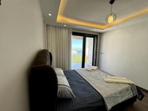 ein Schlafzimmer mit einem Bett und einem großen Fenster in der Unterkunft Karaburun'da Yeni Tripleks BegonVİL-LA in Izmir