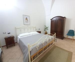 Schlafzimmer mit einem weißen Bett und einem Holzschrank in der Unterkunft Le antiche volte del 1900 in Galatone