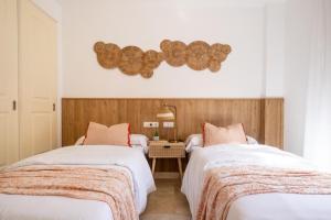 a bedroom with two beds with white sheets and a table at Increíble y Moderno apartamento Duplex con piscinas y preciosas vistas in Estepona