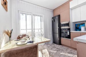 eine Küche mit Tisch und Kühlschrank in der Unterkunft Набережная, небоскребы, кофейня, фитнес, стильно и недорого, ЖК 7Я in Astana