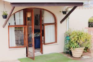 una porta d'ingresso ad arco per una casa con piante in vaso di Vista Garden Cottage a Mbabane