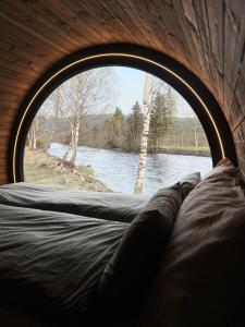 Blick auf einen Fluss durch ein rundes Fenster in der Unterkunft Dreamy Barrel in Ljotegard