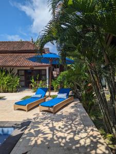 two lounge chairs and an umbrella next to a pool at Indigo Bungalows in Gili Trawangan