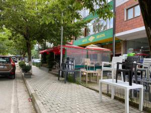 Hotel brazil في Peshkopi: رصيف به كراسي وطاولات على شارع