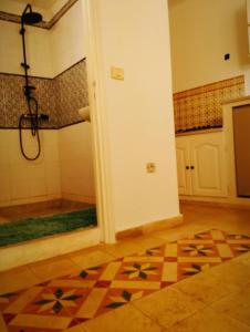 Habitación con baño con ducha y suelo de baldosa. en Maison Albatros, en Mahdia