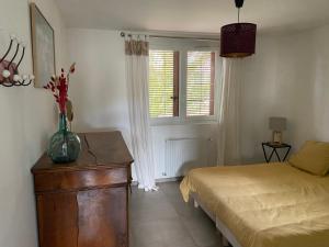 sypialnia z łóżkiem i stołem z wazonem w obiekcie Appartement en Provence-Lubéron - piscine et calme w mieście Volx