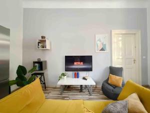 a living room with a yellow couch and a tv at Central Charm in Budapest's Bustling 7th District in Budapest