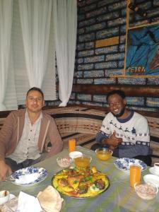 two men sitting at a table with a plate of food at Petra Anas House in Wadi Musa