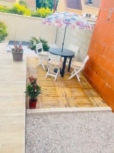 a patio with a table and chairs and an umbrella at Appartement indépendant chez l'habitant in Rosny-sur-Seine