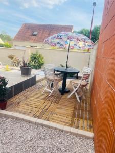 a patio with a table and chairs and an umbrella at Appartement indépendant chez l'habitant in Rosny-sur-Seine
